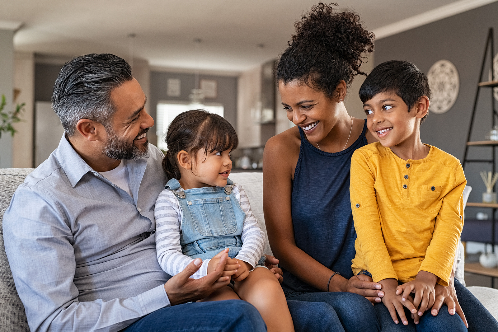 Happy latin family sitting on sofa and laughing together. Middle